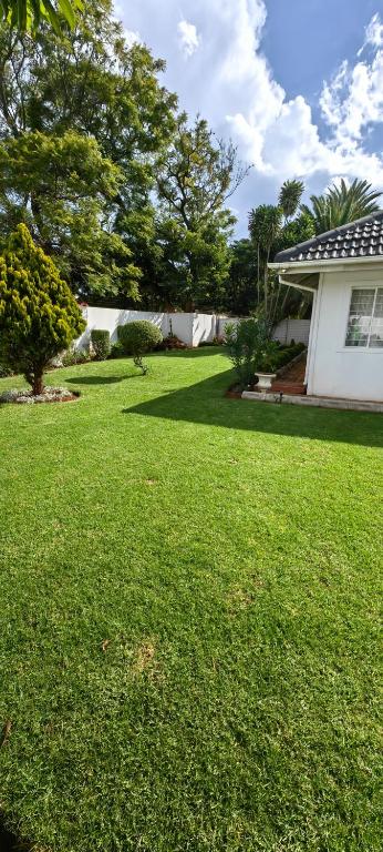 a yard with a white house and a green lawn at 55 On Paisley in Bulawayo