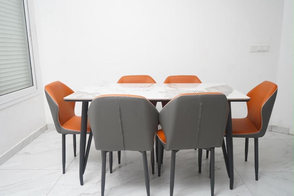 a dining room table with orange chairs around it at residence madame sow in Dakar