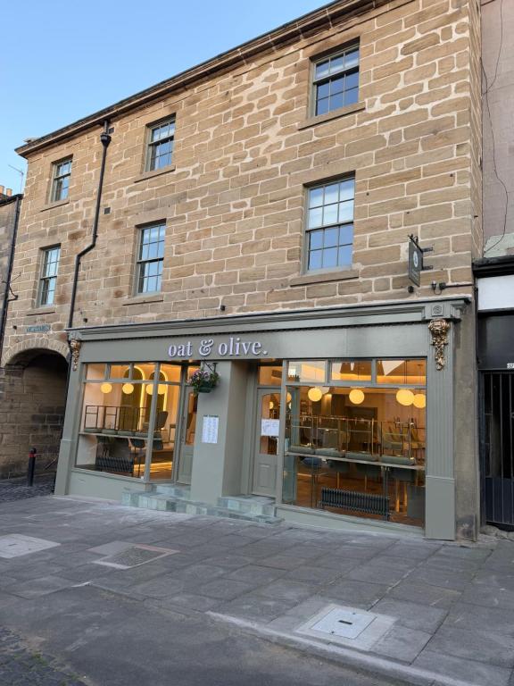 a brick building with a out of alive store at Oat & Olive Apartments - Alnwick in Alnwick
