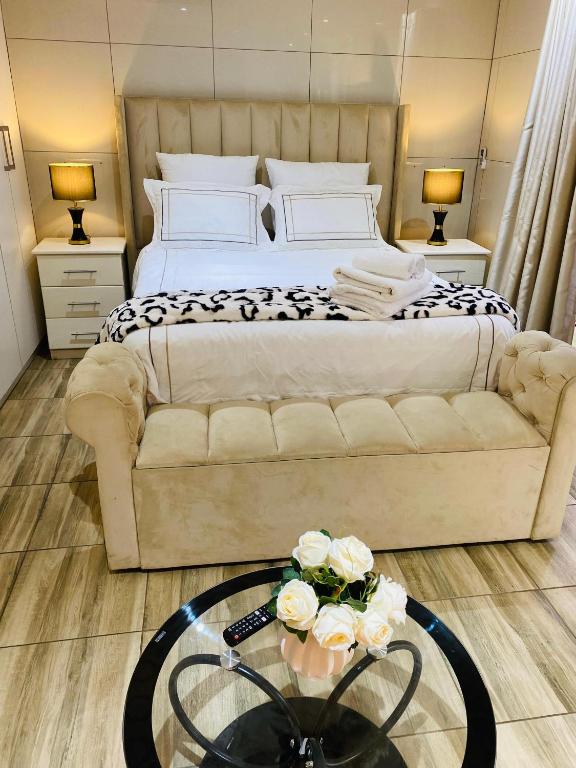 ein Schlafzimmer mit einem Bett und einem Tisch mit Blumen darauf in der Unterkunft Comfy Nest Guest House in Durban