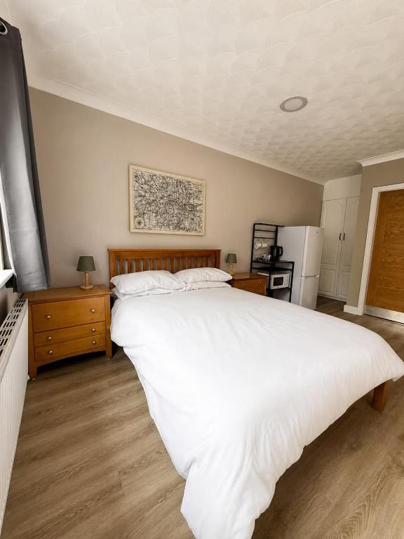 a bedroom with a large white bed and a refrigerator at The Bay Horse Accommodation Contractor Rooms in Carlton