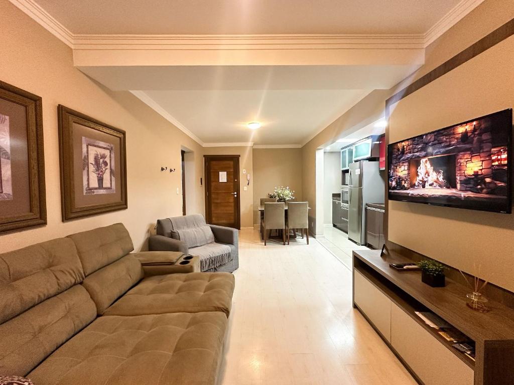 a living room with a couch and a flat screen tv at Canela Dreams - Stay House Temporada in Canela