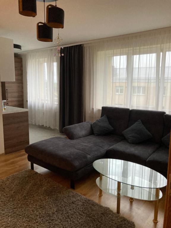 a living room with a couch and a glass table at Mājīgie Apartamenti Saldū in Saldus