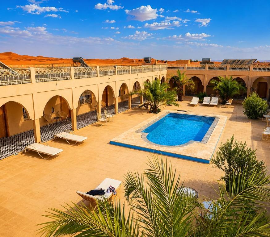 a large courtyard with a swimming pool in the desert at Riad Akabar Merzouga in Merzouga