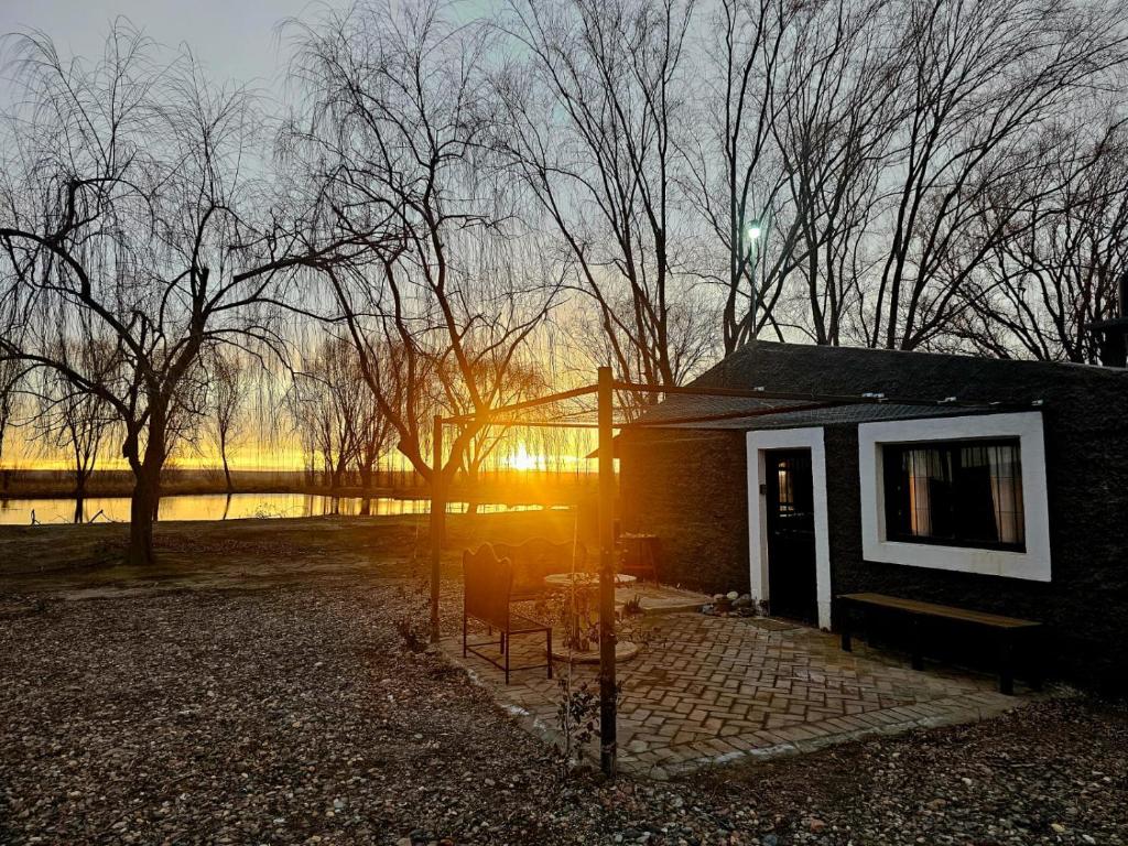 ein kleines Haus mit dem Sonnenuntergang im Hintergrund in der Unterkunft Ruca Raíz - Casa de campo en finca familiar con vista a la montaña, Tupungato in Tupungato