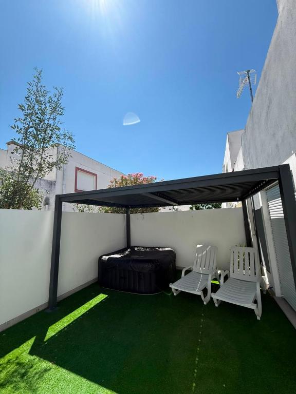 a patio with two chairs and a black canopy at Moradia t2 com Jacuzzi in Aldeia do Mato
