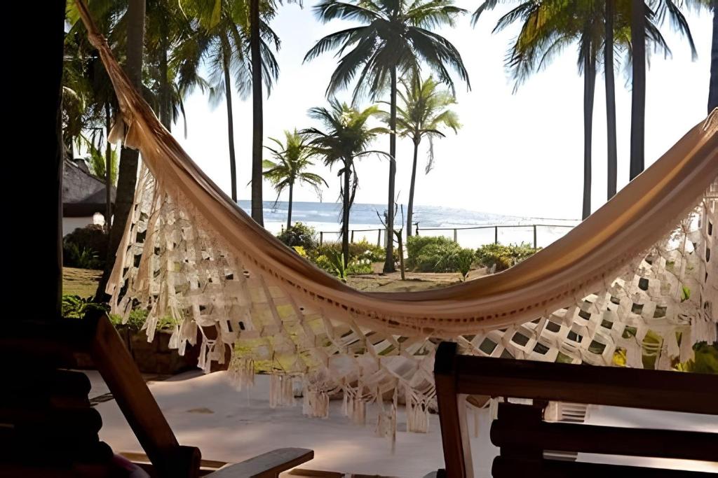 a hammock on a beach with palm trees and the ocean at Casa Capela - Para quem ama ficar na beira do mar in Marau