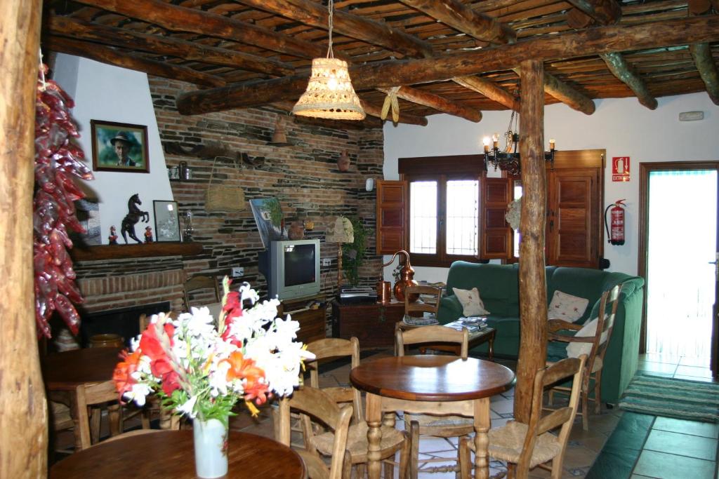 sala de estar con mesas, sillas y TV en Hostal Rural Las Terrazas de la Alpujarra, en Bubión