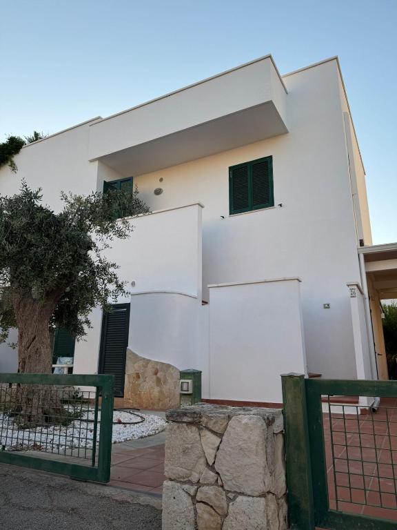 a white house with a fence in front of it at Salento Holiday Home in Torre Inserraglio