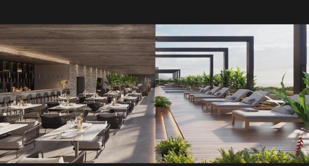 a restaurant with white tables and chairs on a deck at Beach Gav Resort in Ilha de Atalaia