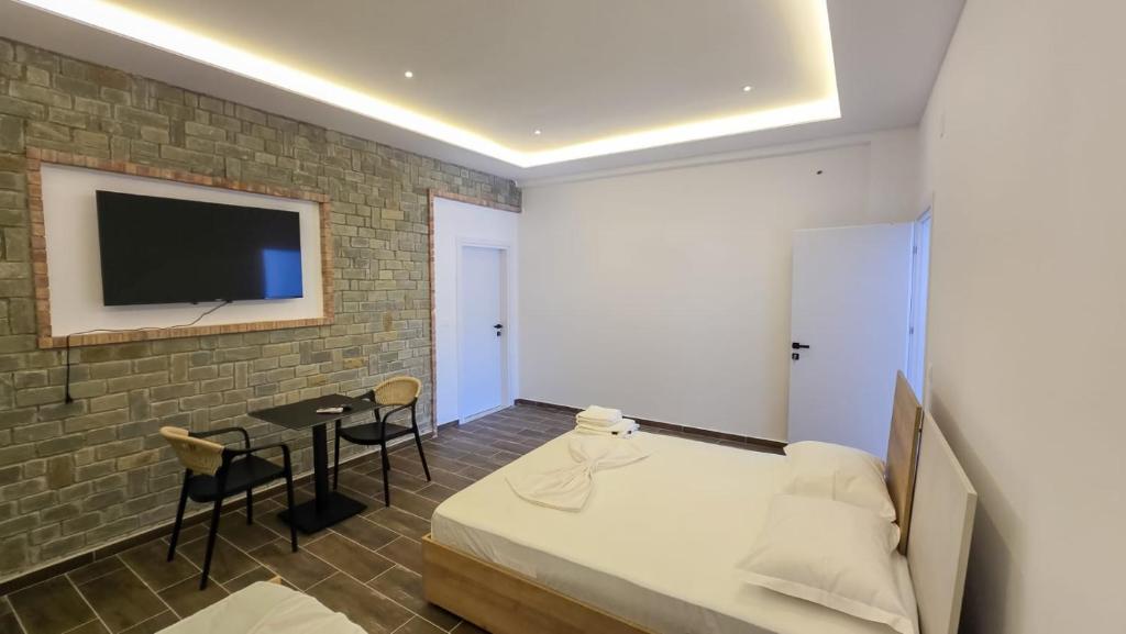 a bedroom with a bed and a tv on a brick wall at Vila Qetesia in Përmet