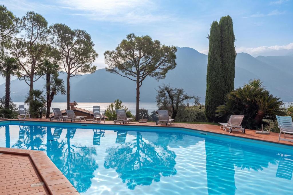 a swimming pool with chairs and mountains in the background at Brentano Giardino in Mezzegra