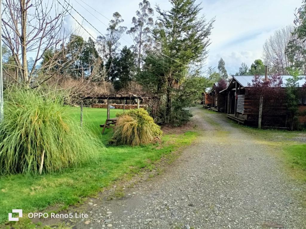 a dirt road next to a barn and some grass at Camping y cabañas Los Parrones in Valdivia