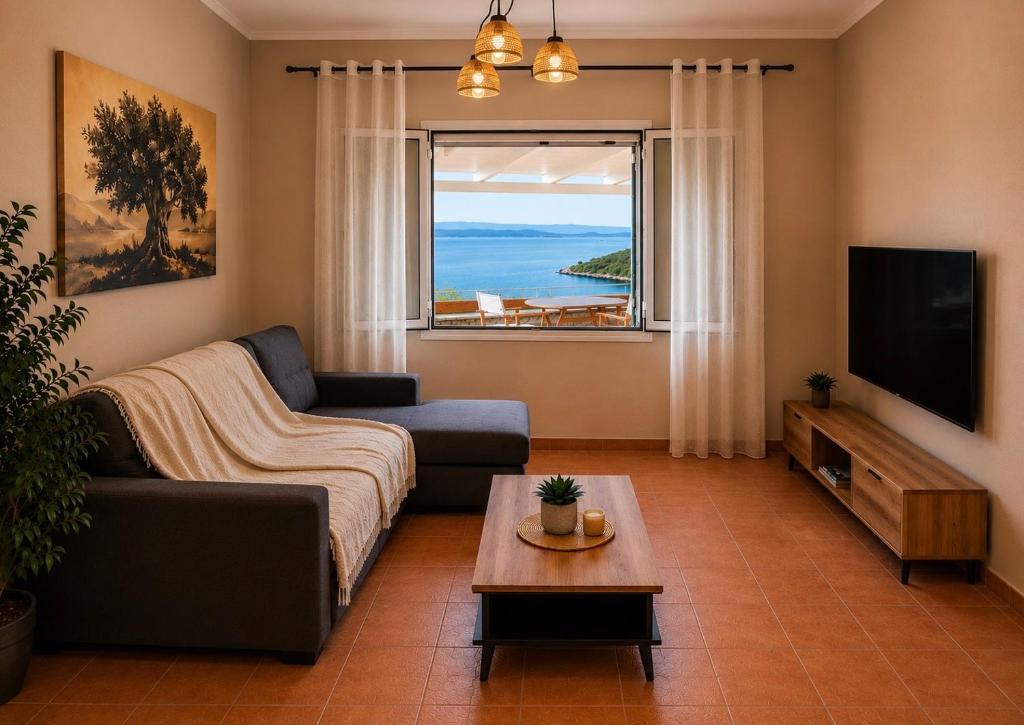 a living room with a couch and a tv and a window at Porto Vigla in Tranakatika