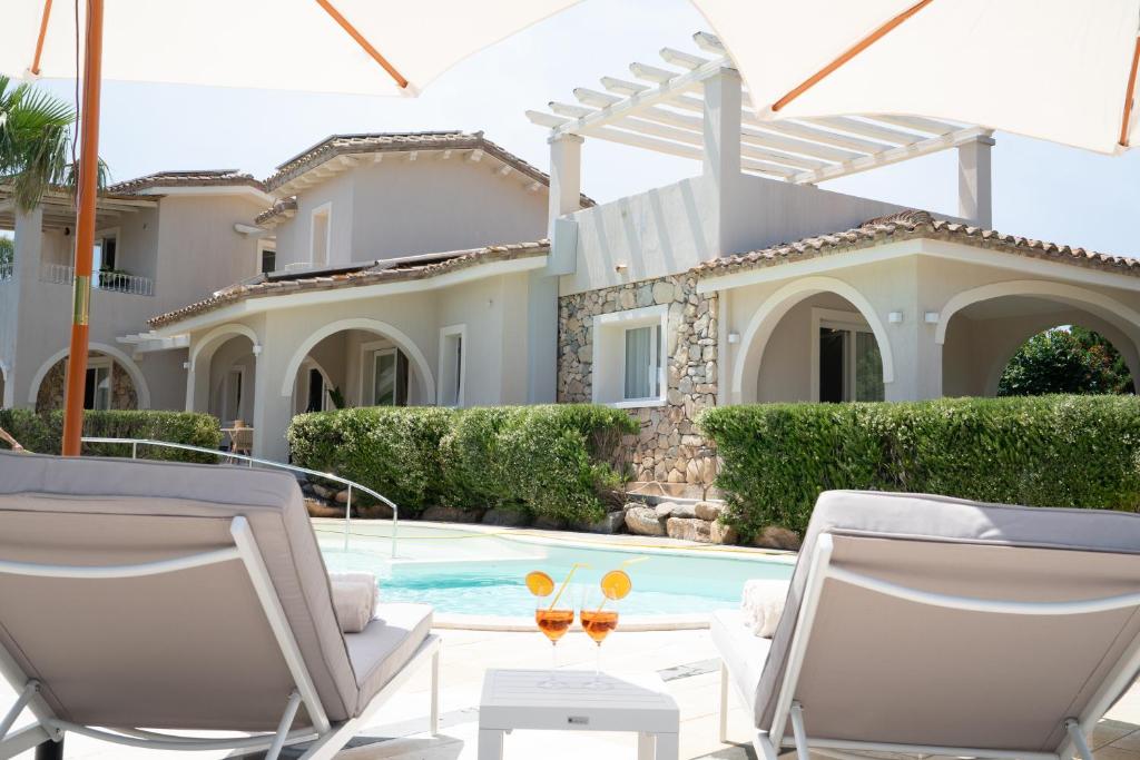 a villa with a swimming pool and two chairs at Appartamenti I Lentischi in Villasimius
