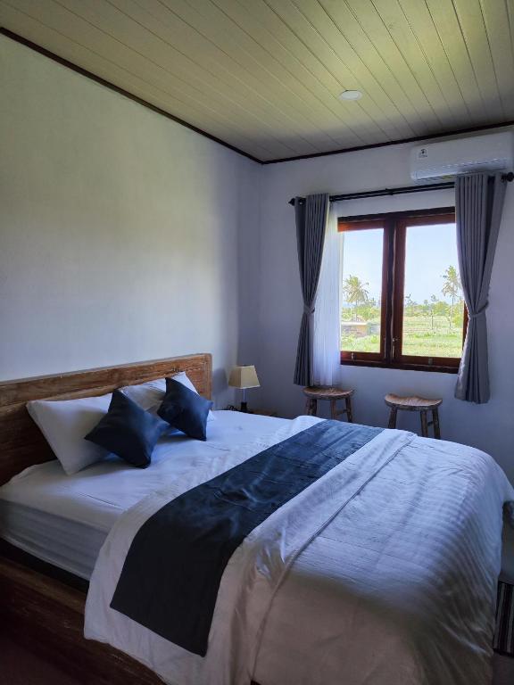 a bedroom with a large bed with blue pillows and a window at MD Amed Guest House in Amed