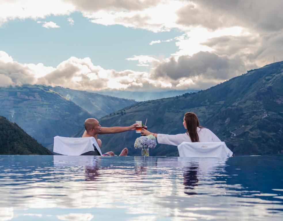 a man and a woman sitting in the water at Luna Volcán, Adventure SPA - formerly Luna Runtún in Baños