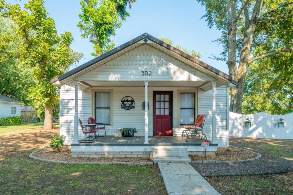 a small white house with two chairs in the front yard at The 1950s Retro Riverside Cottage in Dardanelle