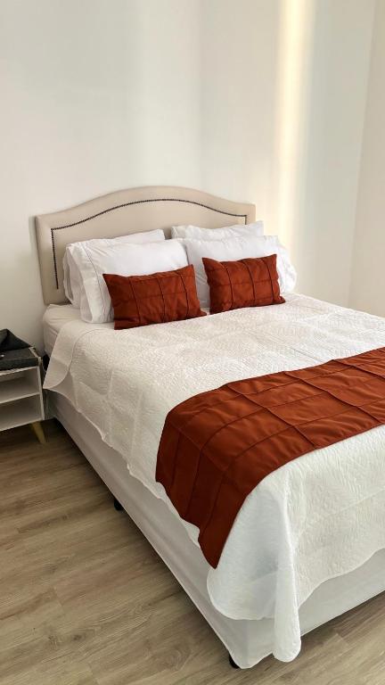 a bedroom with a large bed with red and white pillows at Palladium Refúgio - 500 metros da Praia, Perto do Shopping, Wi-Fi, Piscina e Garagem in São Vicente
