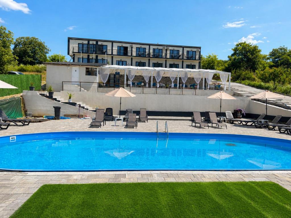 a pool with chairs and umbrellas in front of a building at Casa Amnisty in Liubcova