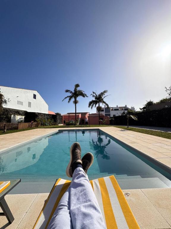 a person laying on a bench next to a swimming pool at Quinta do Rosário in Lagoa