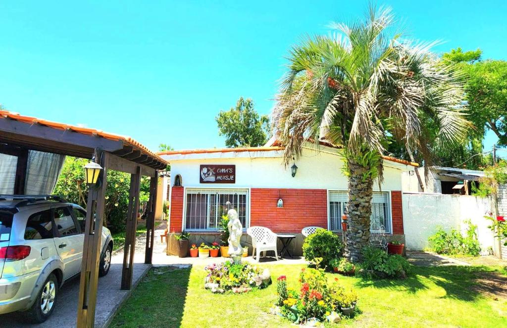 a car parked in front of a house with a palm tree at Bed and Breakfast Omas Huisje in Ciudad de la Costa