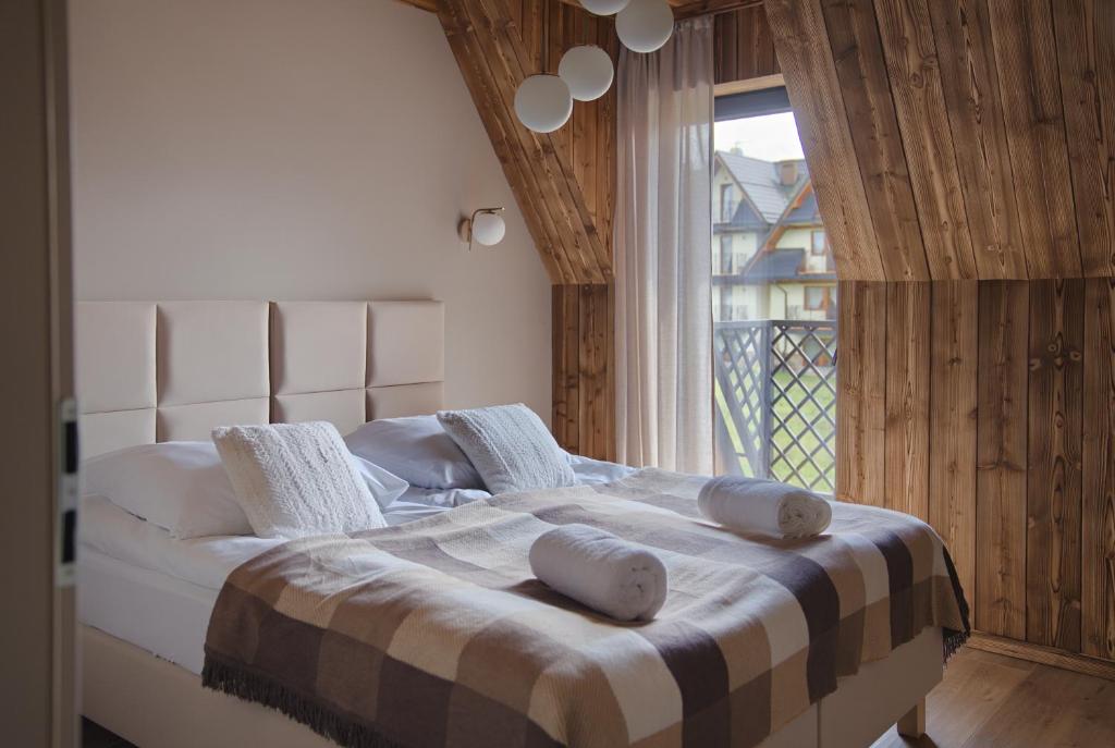 a bedroom with a bed with pillows and a window at Stacja Tatry in Poronin