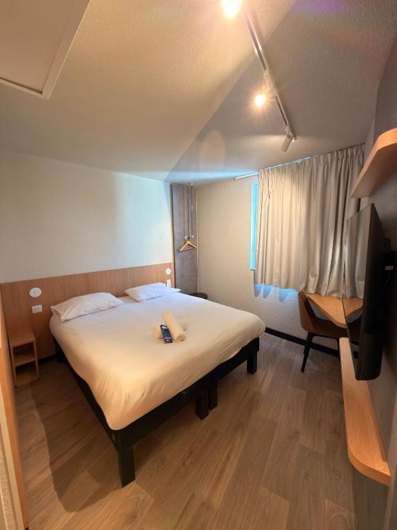 a large bed in a room with a window at Hôtel Inn Design Montluçon in Montluçon