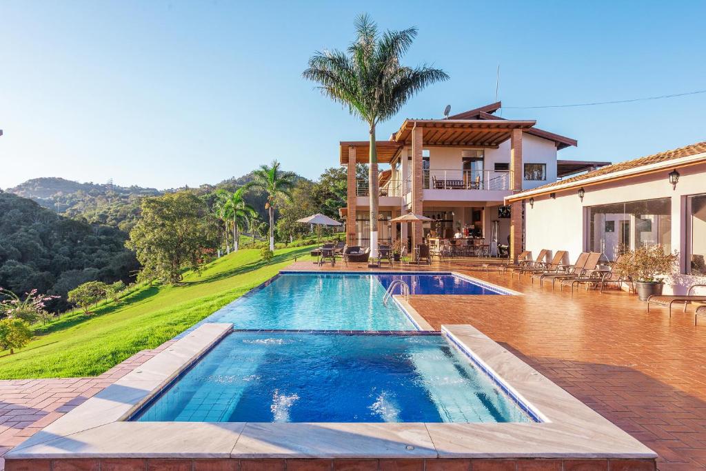 a swimming pool in front of a house at Pousada Estância das Montanhas Boutique in Águas de Lindoia