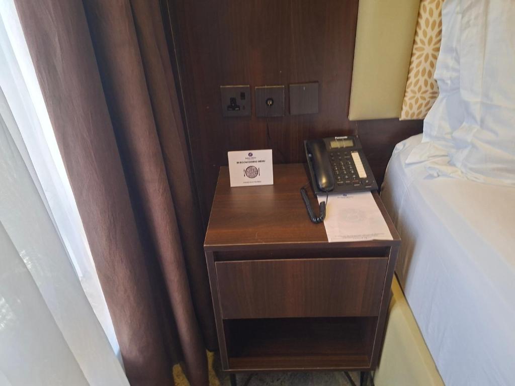 a telephone on a night stand next to a bed at Danville Hotel Ltd in Freetown