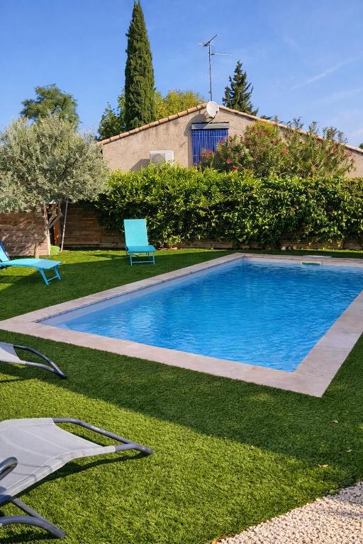 a swimming pool in a yard with a blue chair at Villa J et V in Bédarrides