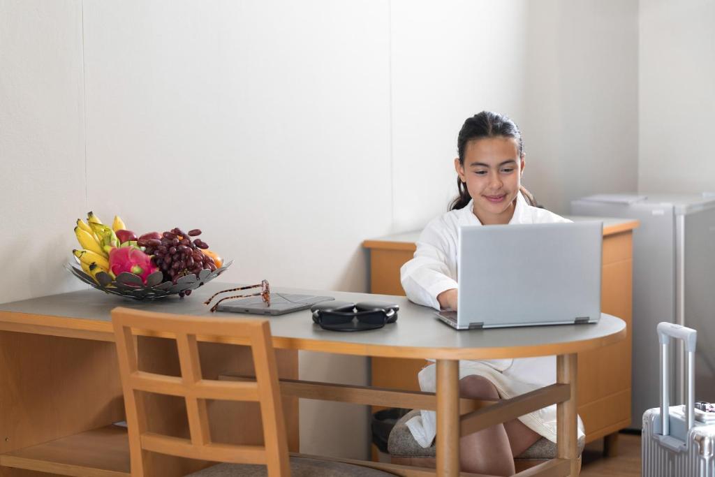 A guest working at a round desk with a laptop and luggage nearby.