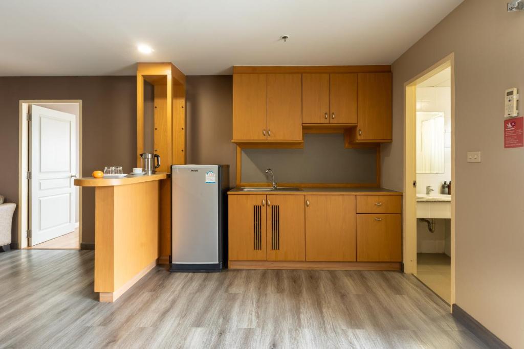 A built-in kitchenette with wood cabinets, sink, compact refrigerator and service counter.