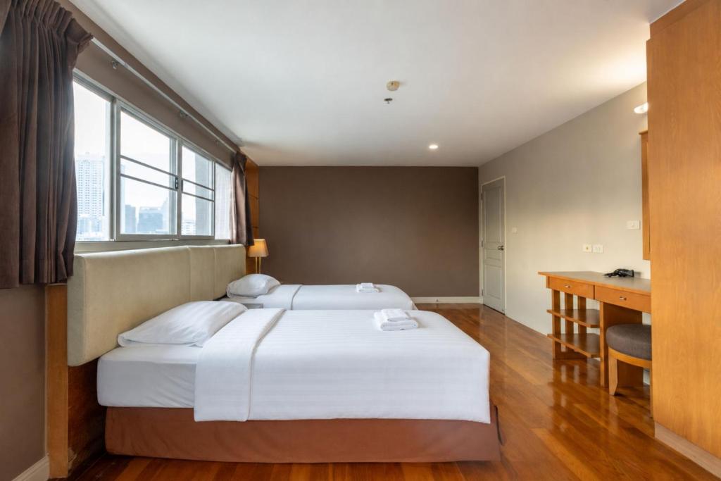 A twin room with two beds, a long window, curtains and a compact desk.