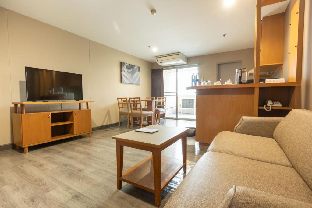 A spacious sitting room with a sofa, television, dining area and kitchenette counter.