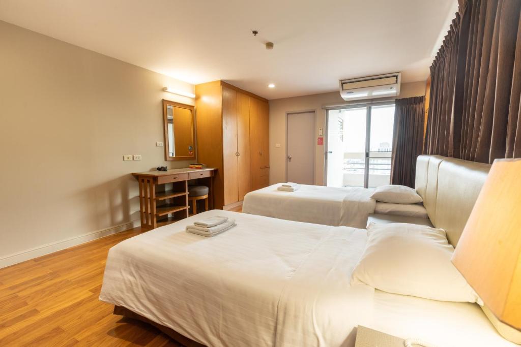 A twin room with two beds, a dressing table, wardrobe and curtained balcony doors.