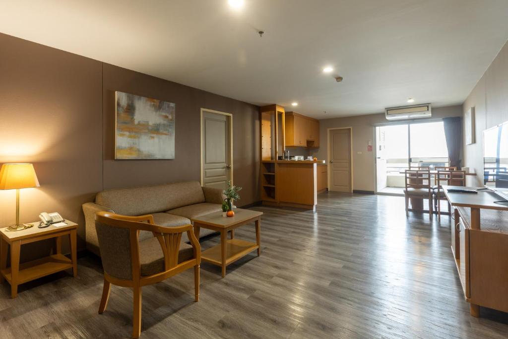 A broad apartment-style living area with lounge seating, kitchenette, dining table and balcony access.