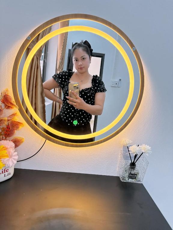 a woman taking a picture of herself in a mirror at N&N Family in Ngân Hà