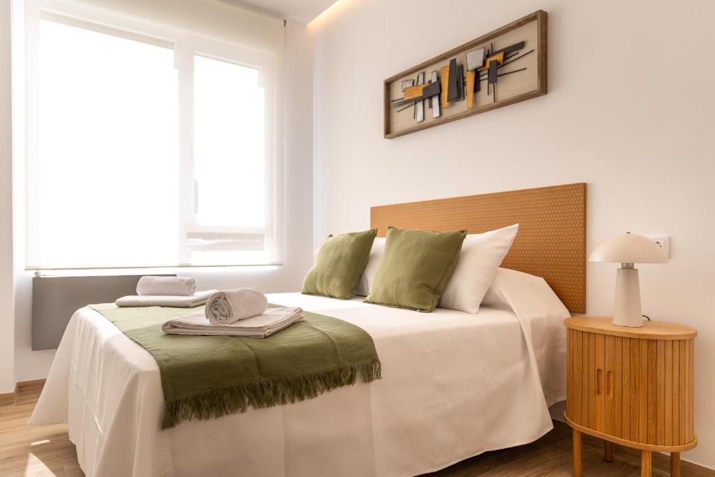 a white bedroom with a bed with a wooden headboard at Apartamentos Liérganes Centro II in Liérganes