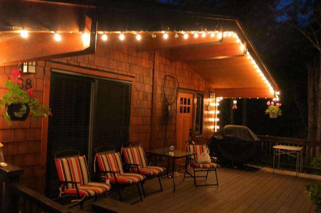 a deck with chairs and a table and lights at A Shack In The Woods in Port Renfrew