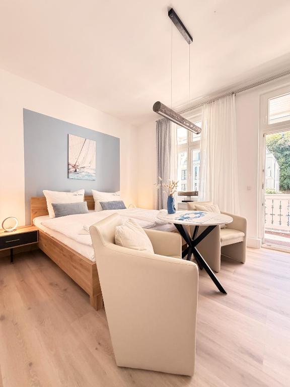 a white bedroom with a bed and a table and chairs at Villa Victoria in Binz
