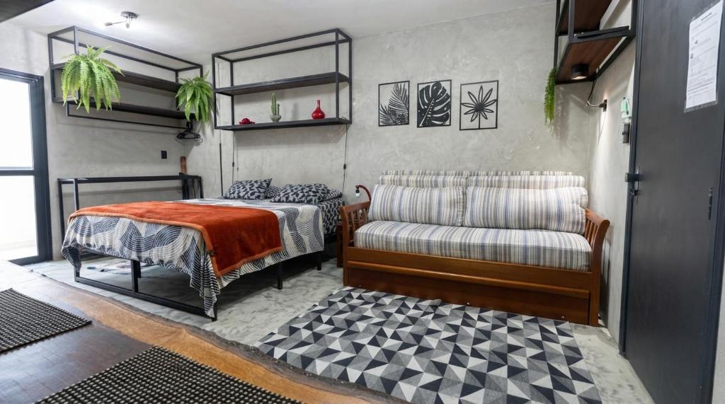 a bedroom with a bed and a couch and a chair at FLAT PALLADIUM - de frente in São Vicente