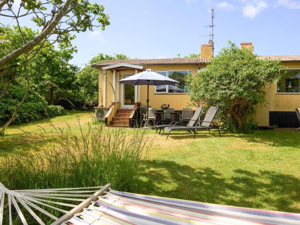 a backyard with a table and chairs and an umbrella at 4 person holiday home in Allinge in Allinge