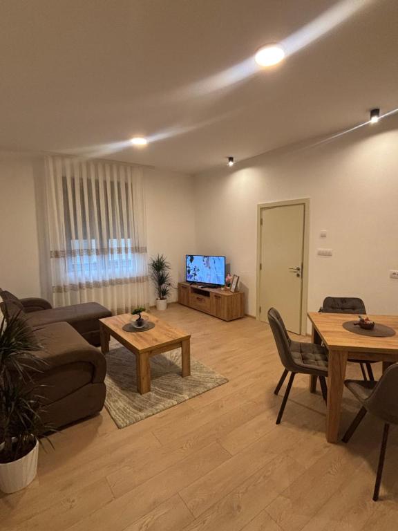 a living room with a couch and tables and a tv at The Central Passage in Gornji Milanovac