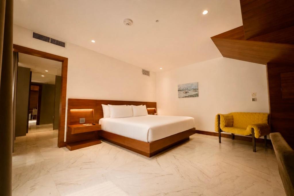 a bedroom with a white bed and a yellow chair at Hotel San Felipe in Panama City