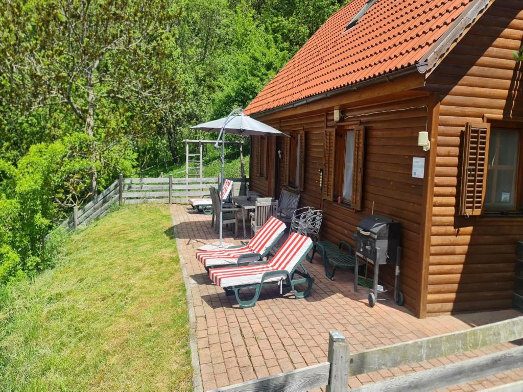 a cabin with a deck with chairs and an umbrella at Karawankenpanorama L in Liebenfels