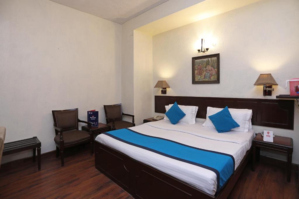a hotel room with a bed and two chairs at Collection O Hamilton Hotel in New Delhi