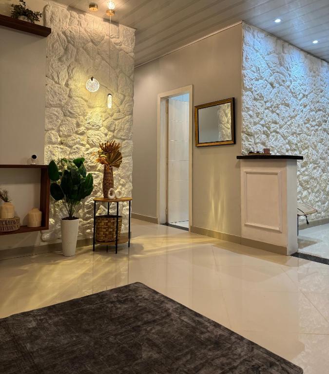 a lobby with a fireplace and a stone wall at Casa Larissa in Presidente Figueiredo