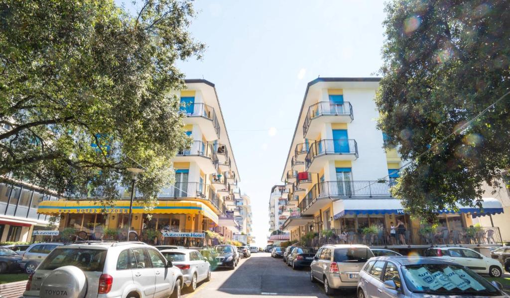 een stadsstraat met auto's geparkeerd voor gebouwen bij Hotel Antille e Azzorre in Lido di Jesolo