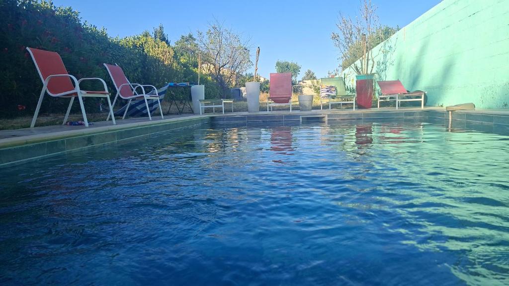 a pool of water with chairs sitting next to it at VILLA BELLA avec piscine et jacuzzi in Saint-Fons
